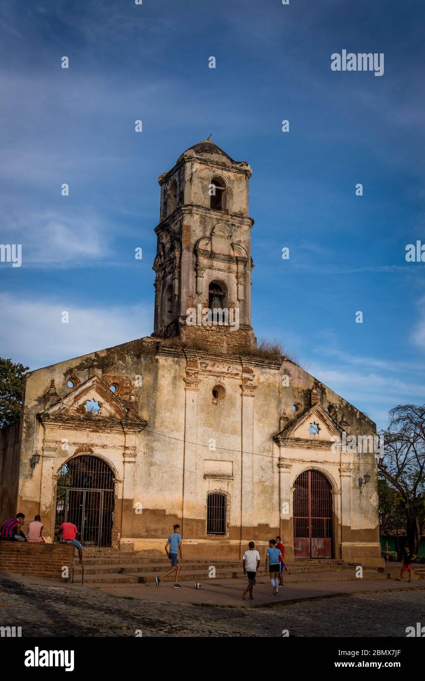 Les enfants jouant au football devant l'église de Saint Ana, Trinidad, Cuba, abandonnée et abandonnée Banque D'Images