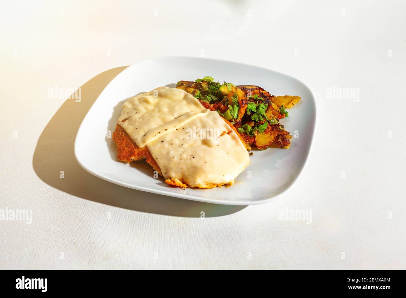 Schnitzel au fromage gratin avec pommes de terre frites sur une plaque blanche - isolé sur blanc Banque D'Images