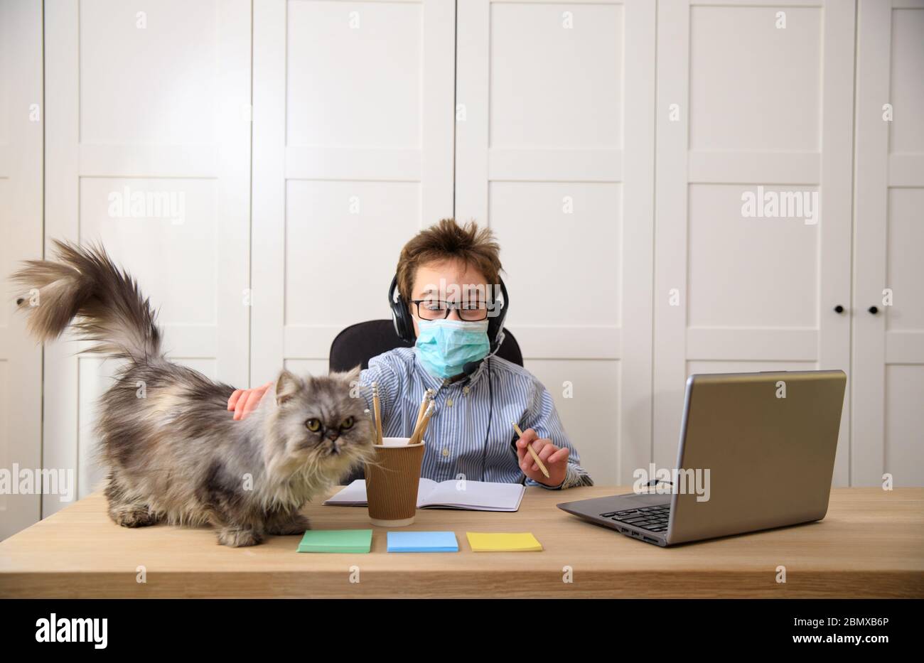 Enseignement en ligne à distance. Un garçon étudie à la maison et fait ses devoirs à l'école. Un apprentissage à distance à domicile , pandémie de coronavirus dans le Banque D'Images