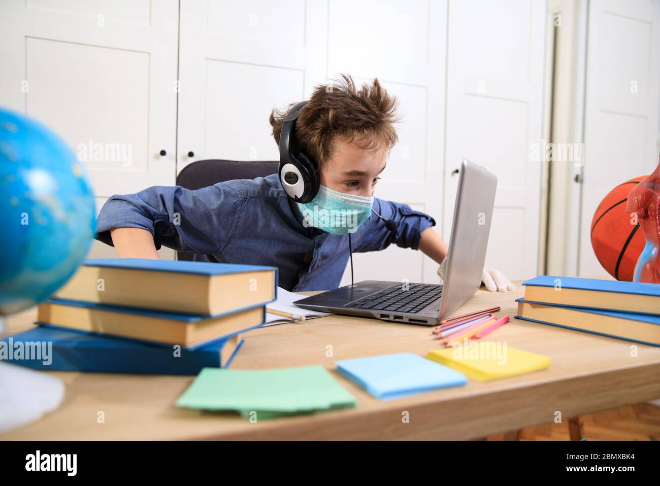 Enseignement en ligne à distance. Un garçon étudie à la maison et fait ses devoirs à l'école. Un apprentissage à distance à domicile , pandémie de coronavirus dans le Banque D'Images