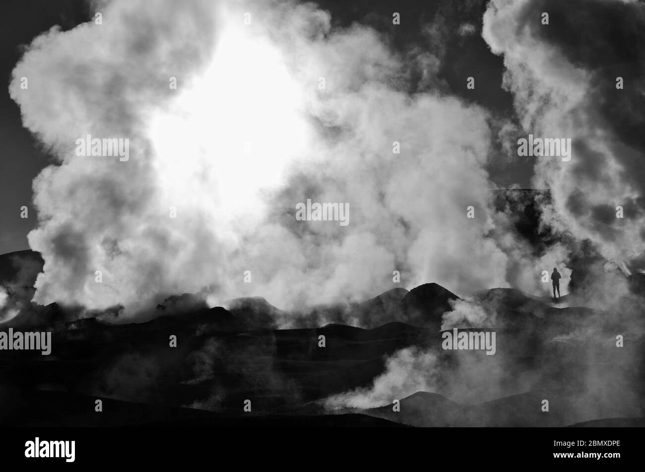 Homme contre sauvage. De la fumée sort du sol partout. Un petit homme apparaît à travers les colonnes énormes de fumée. C'est une scène en noir et blanc. Banque D'Images