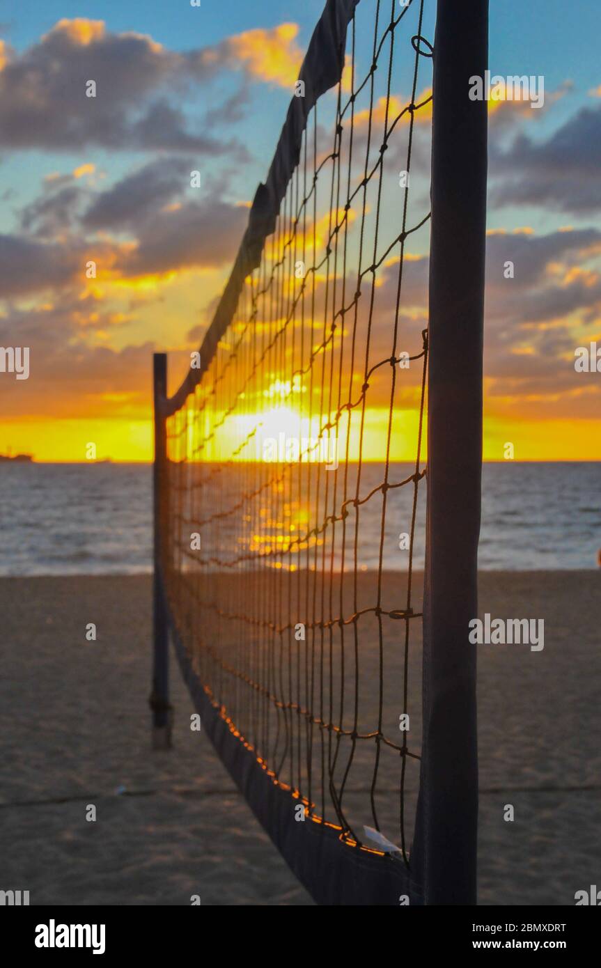 Filet de volley-ball est silhoueted contre le lever du soleil sur un terrain de Beach volley. Banque D'Images