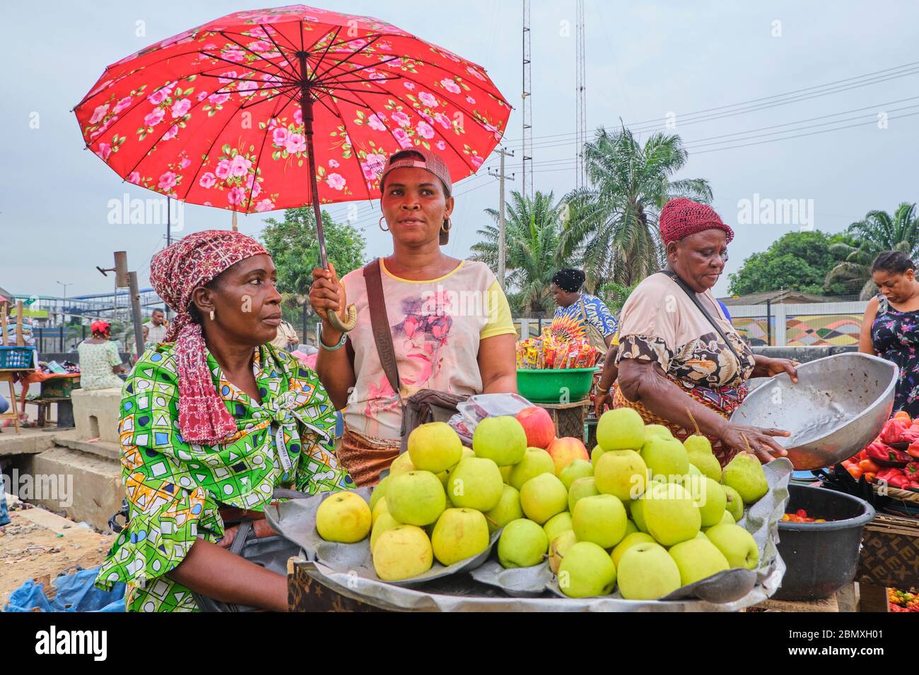 Commerçants vendant des pommes et des légumes sur un marché à Lagos, au Nigeria. Banque D'Images