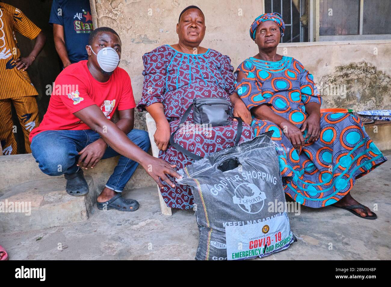 Un volontaire remet un sac alimentaire à deux femmes lors du confinement de Covid-19 à Lagos, au Nigeria. Banque D'Images