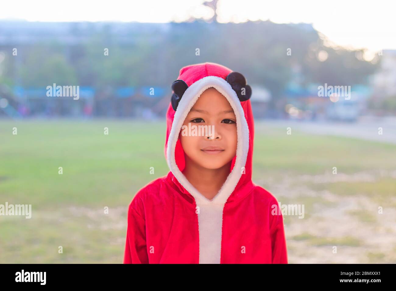 Un garçon asiatique portant un fond de Noël rouge sur la pelouse de l'école. Banque D'Images