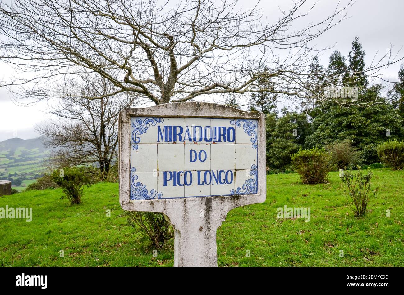 Signe bleu Miradoiro do Pico Longo, point de vue Pico Longo en anglais, sur des tuiles typiquement portugaises. Herbe et arbres sans feuilles en arrière-plan. Photo horizontale. Banque D'Images
