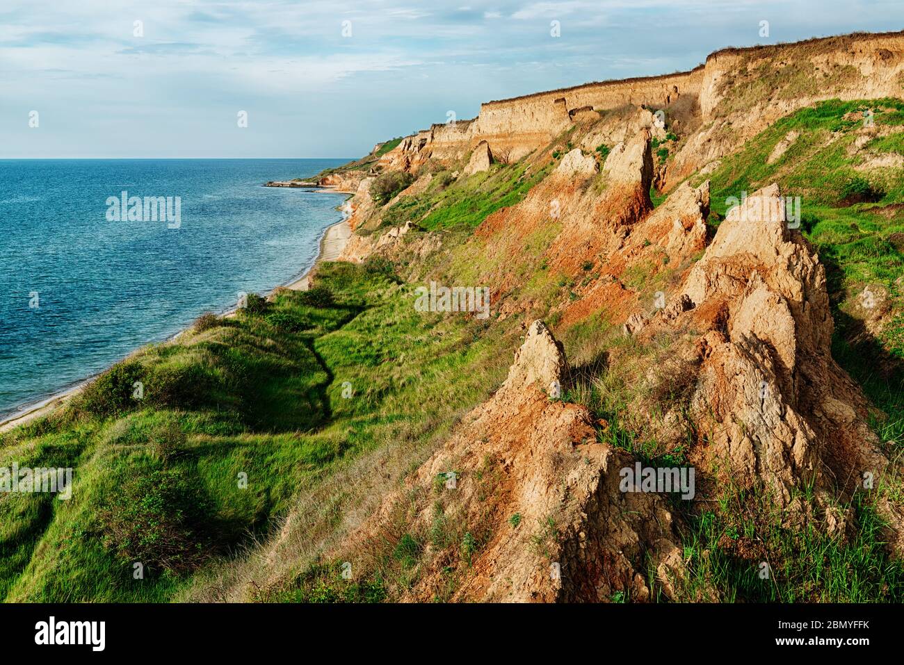 Côte de mer pittoresque avec falaises argileuses colorées et ciel sombre Banque D'Images