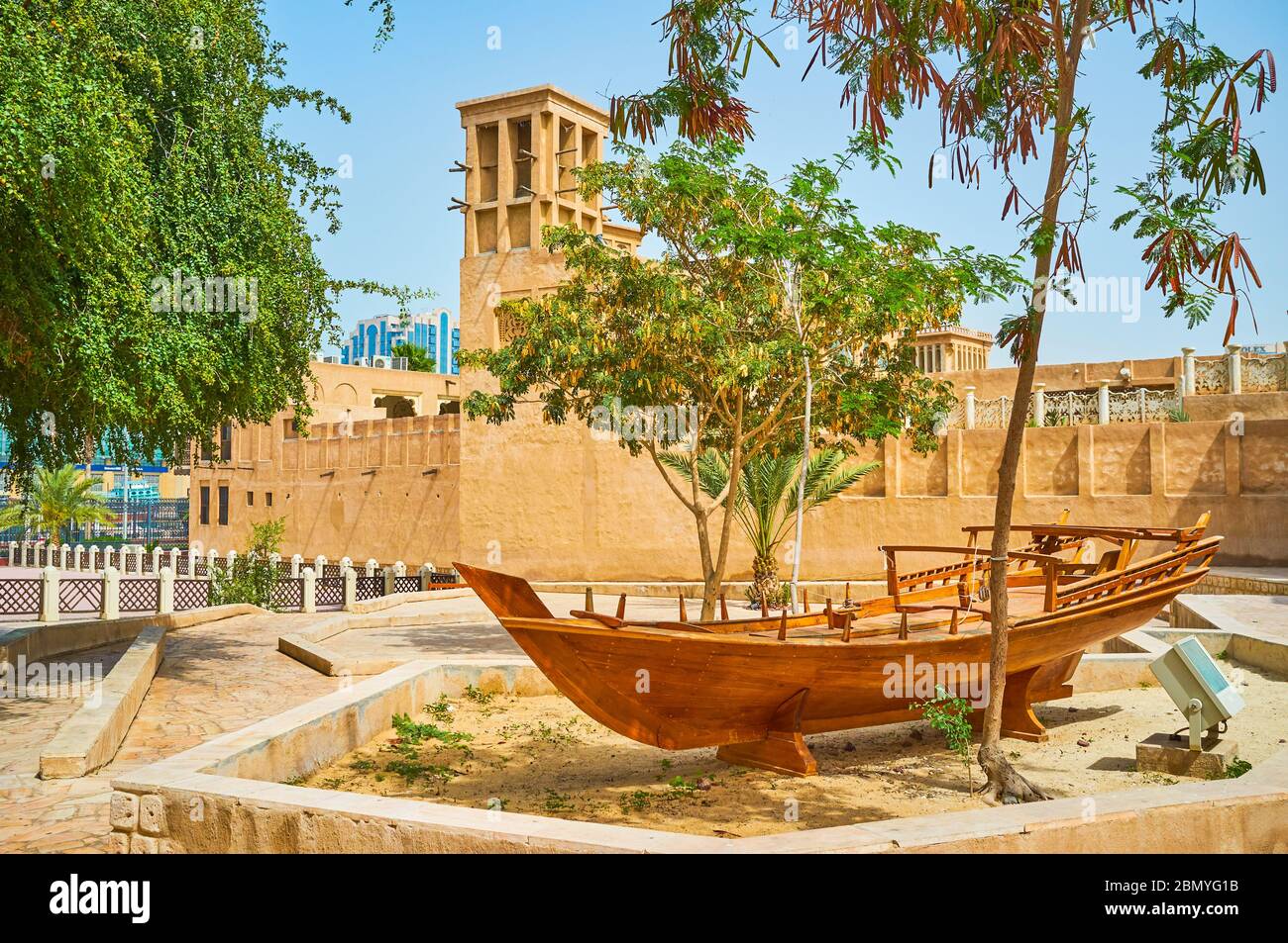 Le petit parc d'Al Bastakiya est décoré avec un bateau de pêche d'époque, debout sur la plate-forme de sable en face de la maison historique en argile avec barjeel W. Banque D'Images