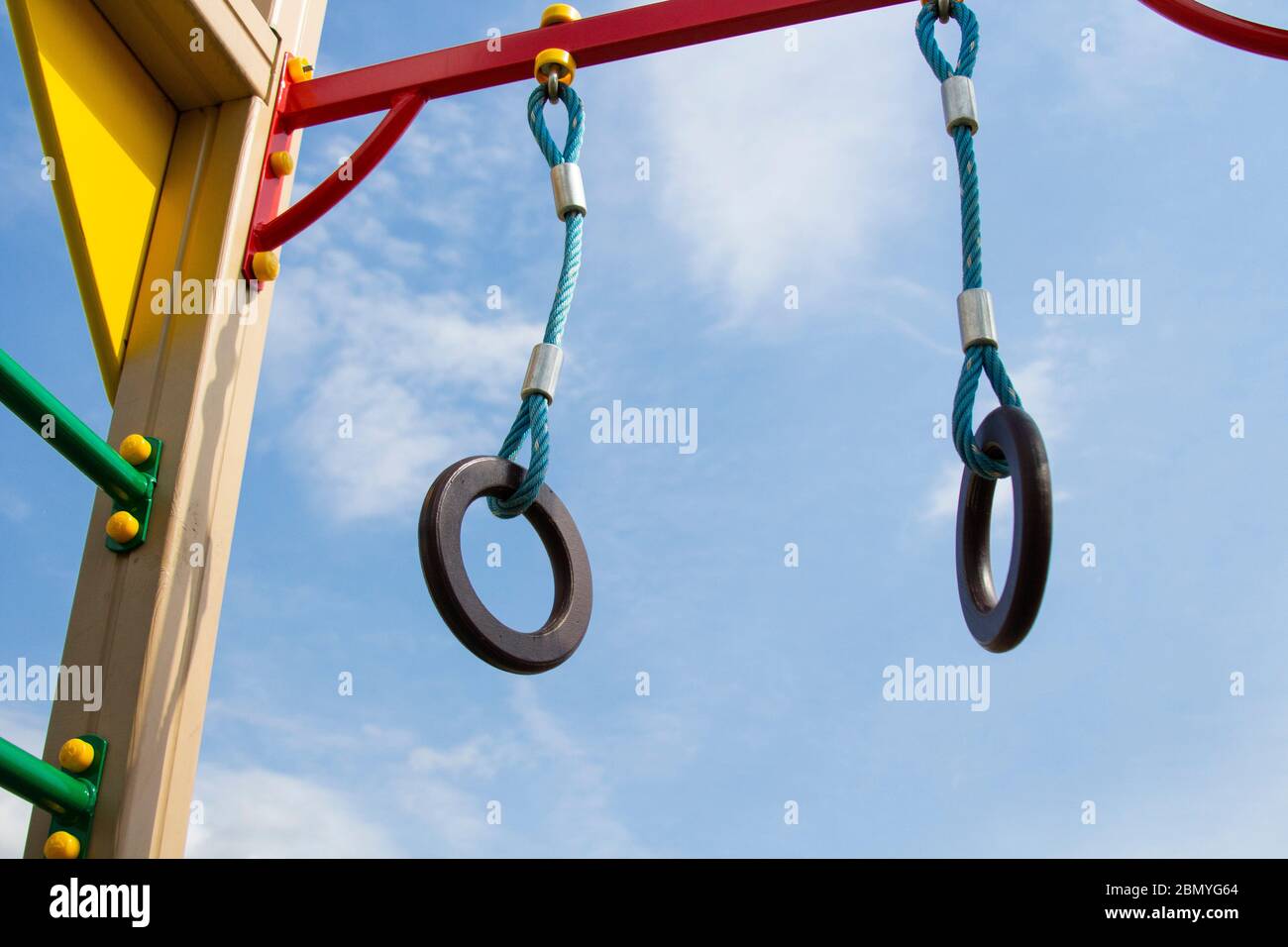 Des anneaux de gymnastique sont suspendus sur l'aire de jeux, sur la barre horizontale. Contre le ciel bleu. Banque D'Images