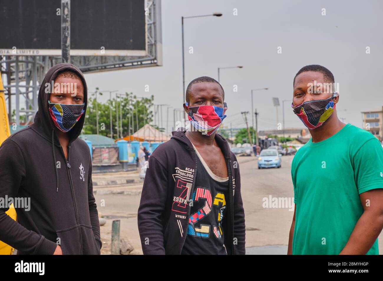 Trois amis, Ramsy, Michael et Dayo, posent pour une photo tout en balançant leur masque ankara à Lagos, Nigeria. La plupart des gens se mettent maintenant en costume Banque D'Images