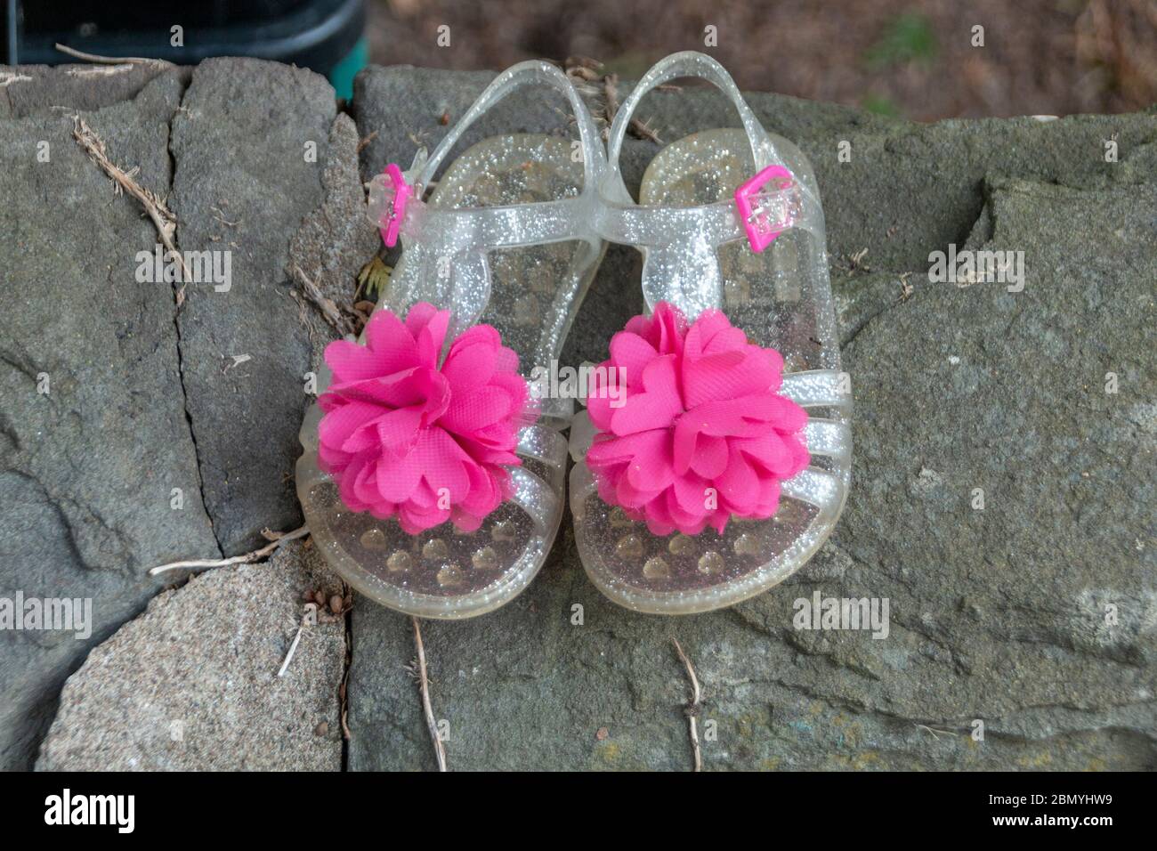 une vue rapprochée d'une petite paire de chaussures en plastique transparent pour filles avec une jolie fleur rose sur le devant Banque D'Images
