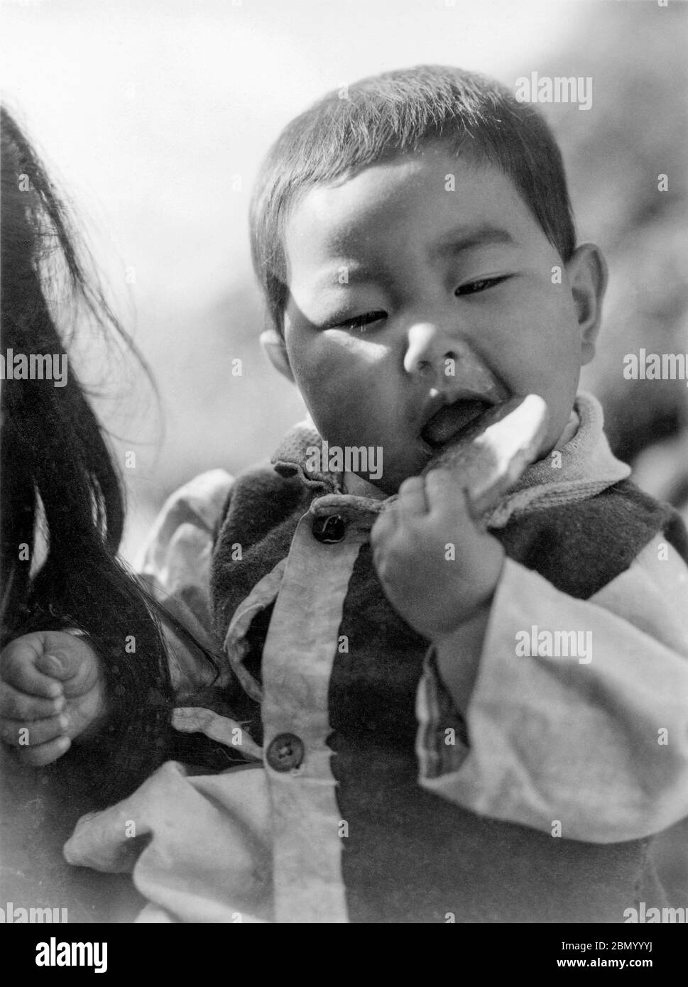 [ 1946 Japon - Garçon d'Okinawa ] — garçon d'Okinawa mangeant un biscuit, 1946 (Showa 21). imprimé gélatine argent du xxe siècle. Banque D'Images