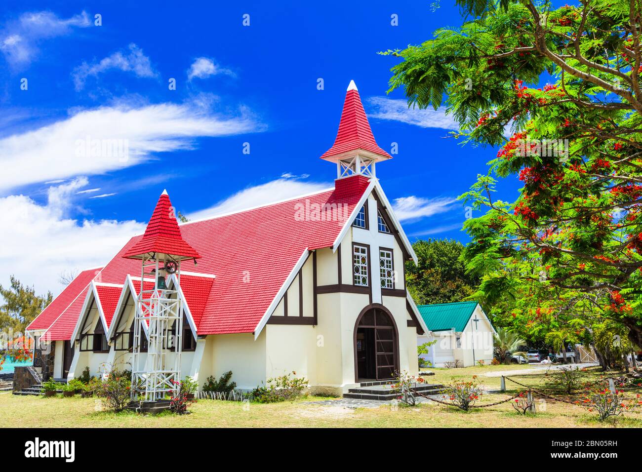 Monuments de la belle île Maurice - Église rouge avec arbre flamboyant en fleurs, Cap Malheureux. Banque D'Images