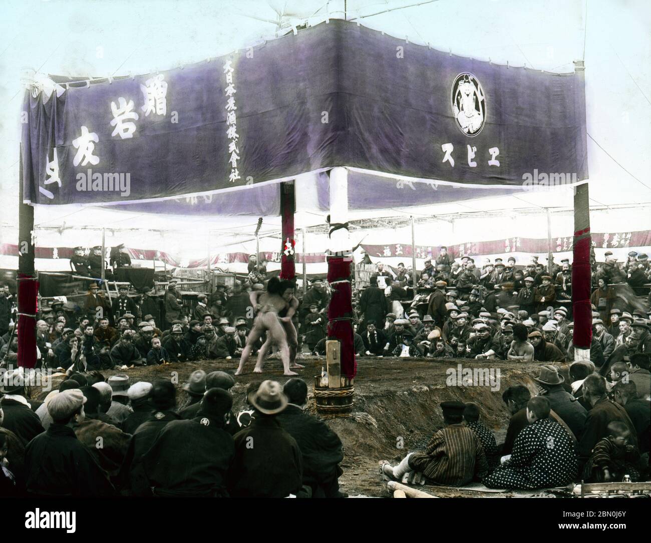 [ 1900s Japon - en dehors de l'arène de Sumo Wrestling au Temple ] — les lutteurs de Sumo dans une arène extérieure au Temple d'Eko-in (回向院) à Ryogoku, Tokyo prêt à commencer un combat. Le temple était connu comme un lieu de lutte sumo pendant les périodes Edo (1603-1868) et Meiji (1868-1912). La première rencontre a eu lieu ici en septembre 1768. Du 1833 octobre (Tenpo 4) au 1909 octobre (Meiji 42), période de "Eko-in Sumo" (回向院相撲), tous les tournois de sumo ont eu lieu au temple. diapositive en verre vintage du xixe siècle. Banque D'Images