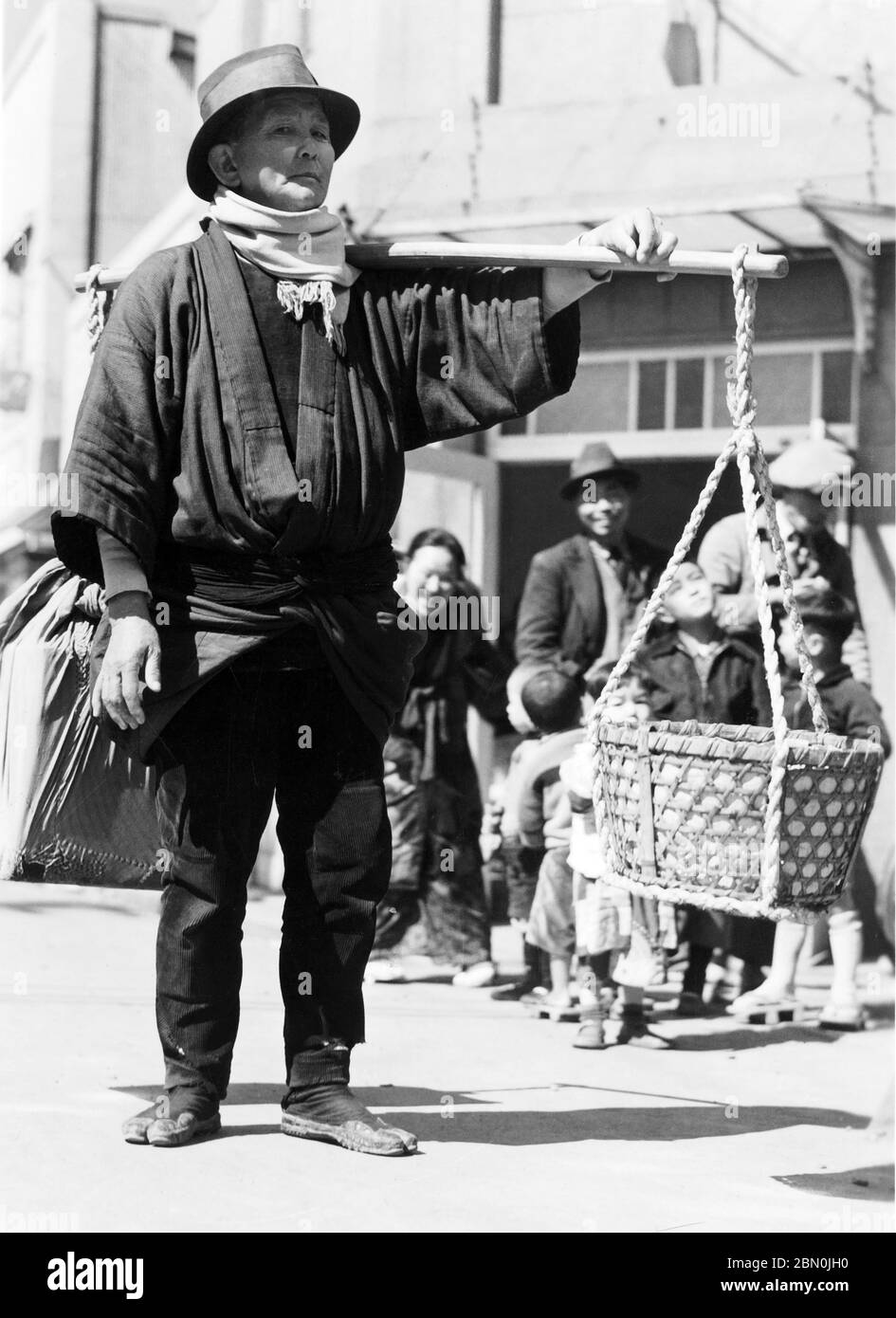 [ Japon des années 1930 - ouvrier japonais ] — OUVRIER à Kobe avec un mât de transport Tenbinbo (天秤棒). imprimé gélatine argent du xxe siècle. Banque D'Images