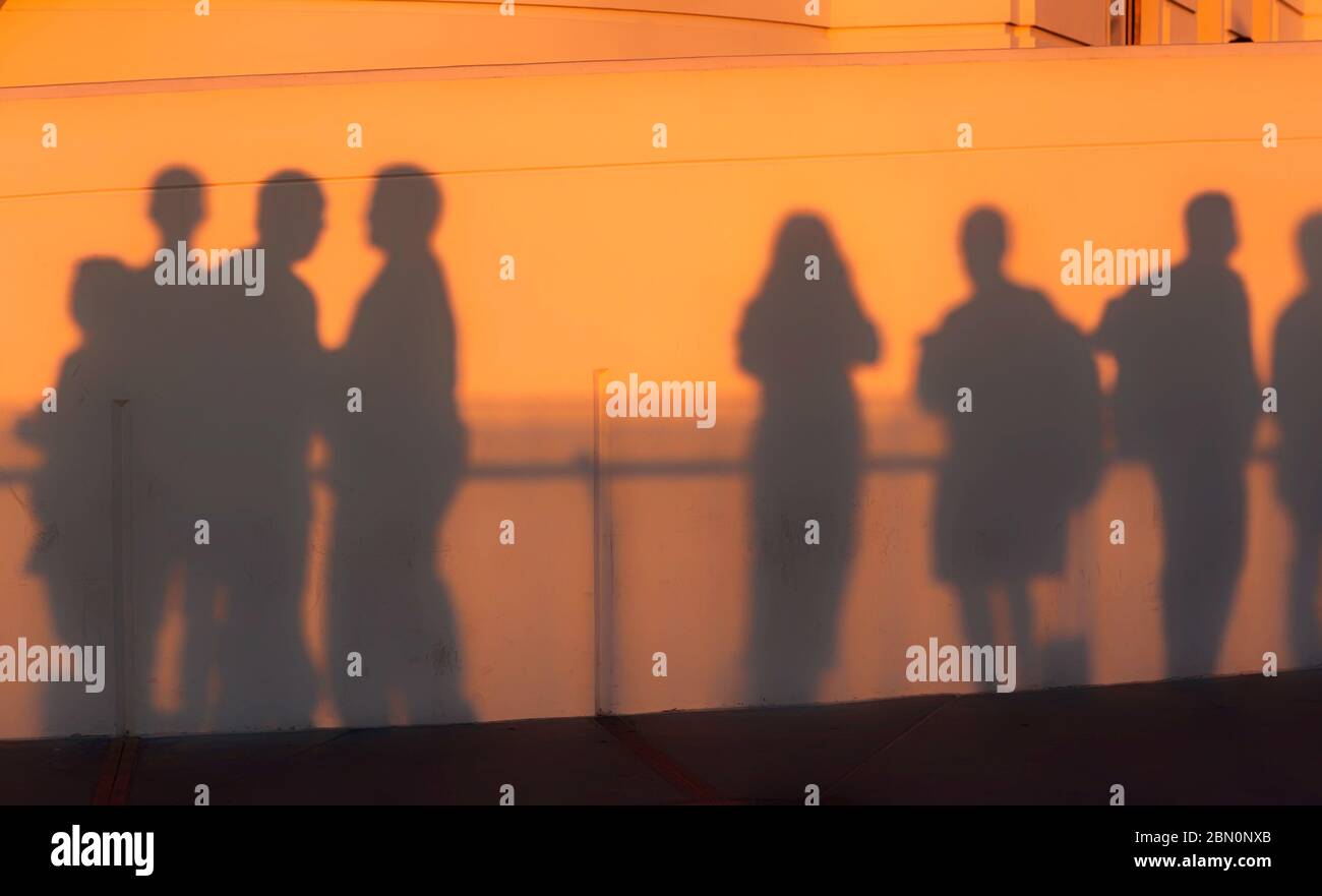 Les visiteurs jettent des ombres sur le mur de l'observatoire Griffith Park au coucher du soleil tout en observant la couleur de Los Angeles, Californie, États-Unis Banque D'Images