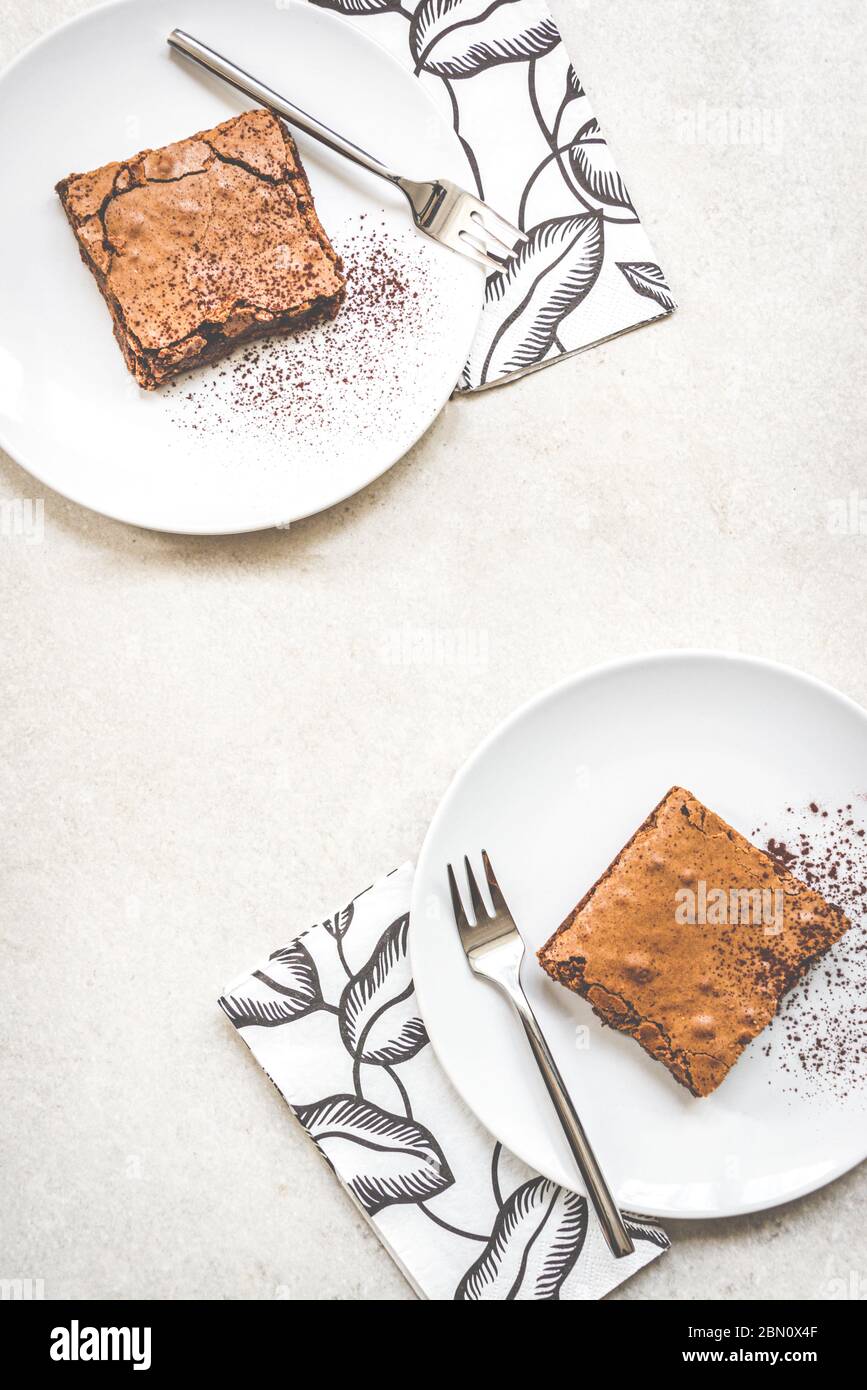 Vue de dessus de deux plats à dessert avec gâteau au brownie sur fond rustique blanc. Banque D'Images