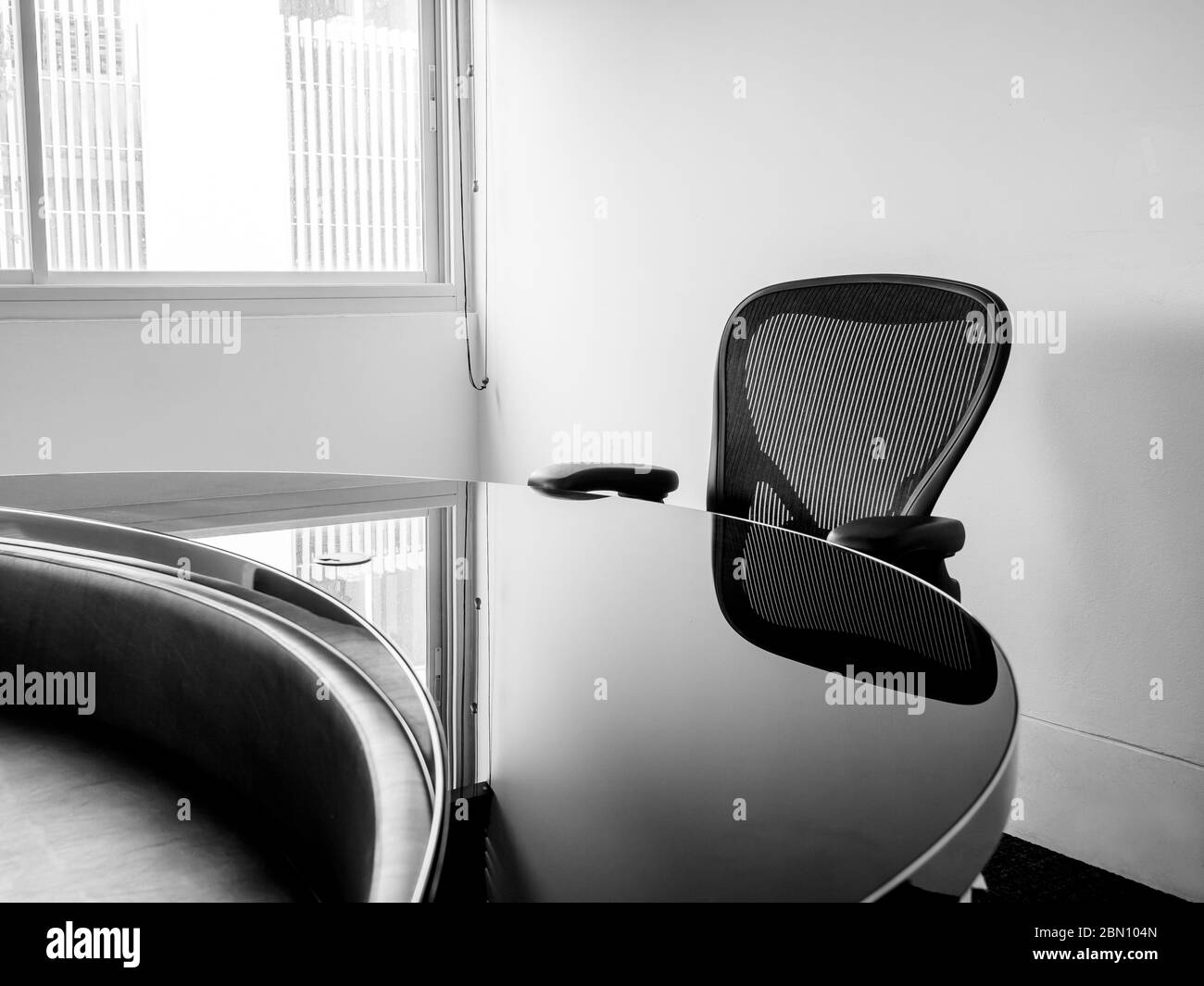 Décoration moderne de la salle de conférence avec table incurvée noire et chaise saine noire près de la fenêtre en verre. Salle de réunion blanche dans le bureau. Banque D'Images