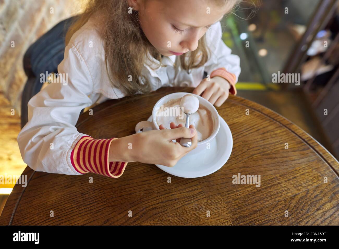 Fille enfant de 9 ans, 10 ans avec une tasse de chocolat chaud assis dans un café à la table Banque D'Images