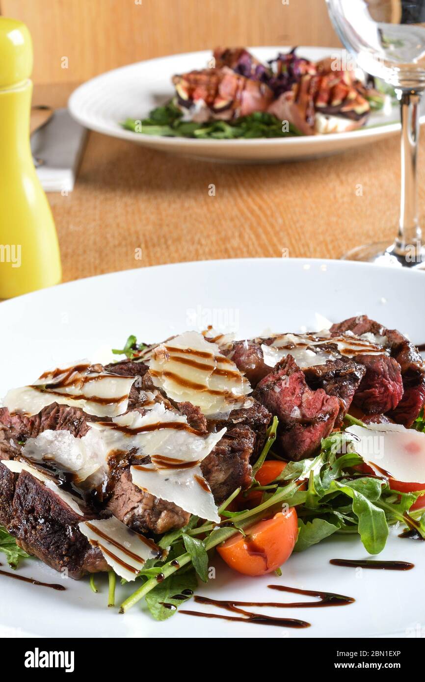 Plat principal italien traditionnel. Tagliata de boeuf : oeil de côte de boeuf tendre, arugula, tomates cerises, copeaux de Grana Padano, réduction balsamique. Emilie-Romagne Banque D'Images
