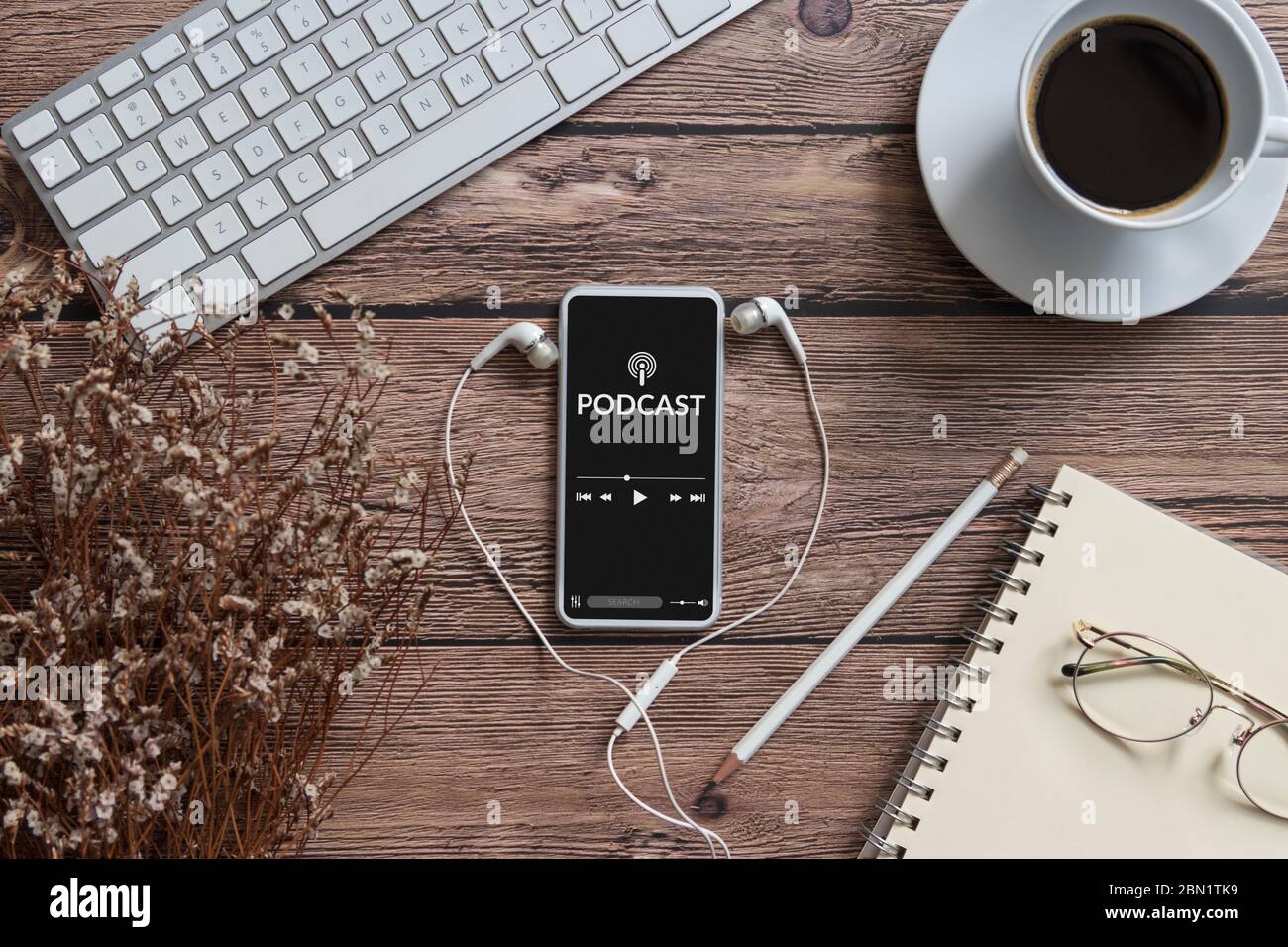 concept de contenu audio podcast. application podcast sur écran de smartphone mobile sur table en bois avec tasse à café, écouteurs, lunettes, ordinateur portable Banque D'Images