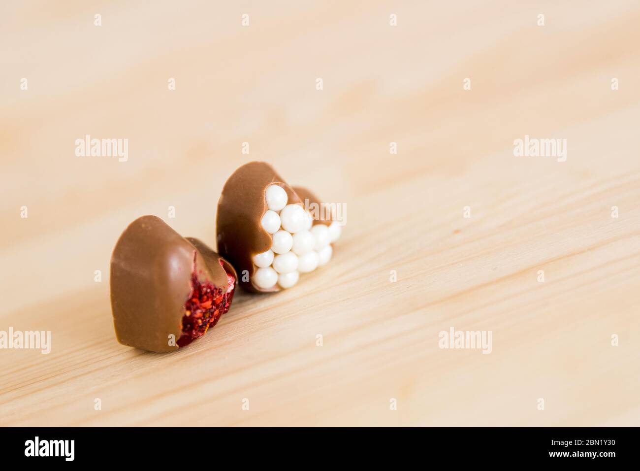 Deux chocolats en forme de coeur d'artisanat avec garniture rouge et blanche se trouvent sur une table en bois. Espace de copie Banque D'Images