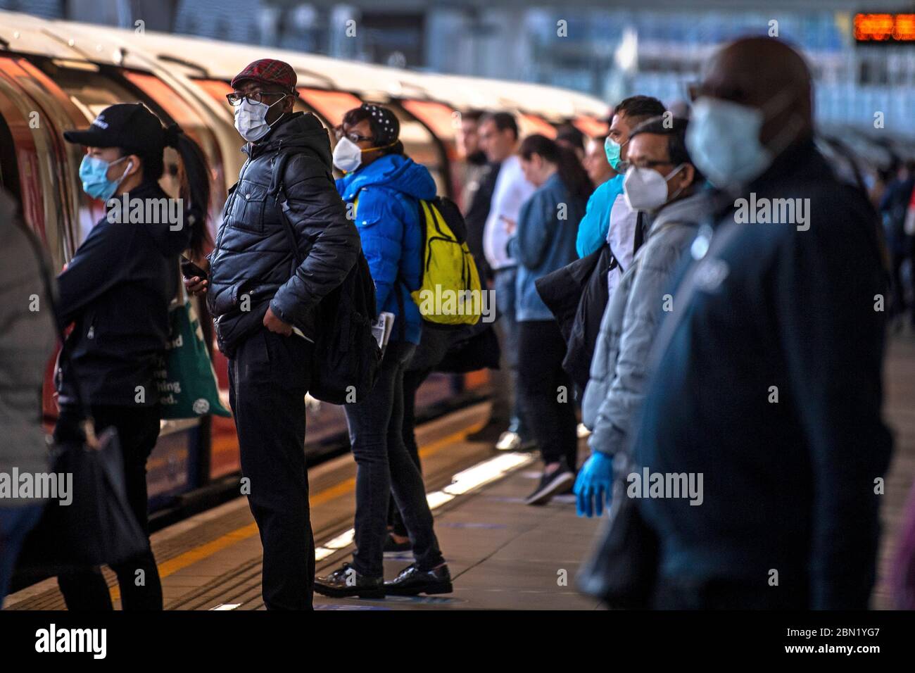 Passagers portant un masque facial sur une plate-forme à la station de métro Canning Town de Londres. Banque D'Images