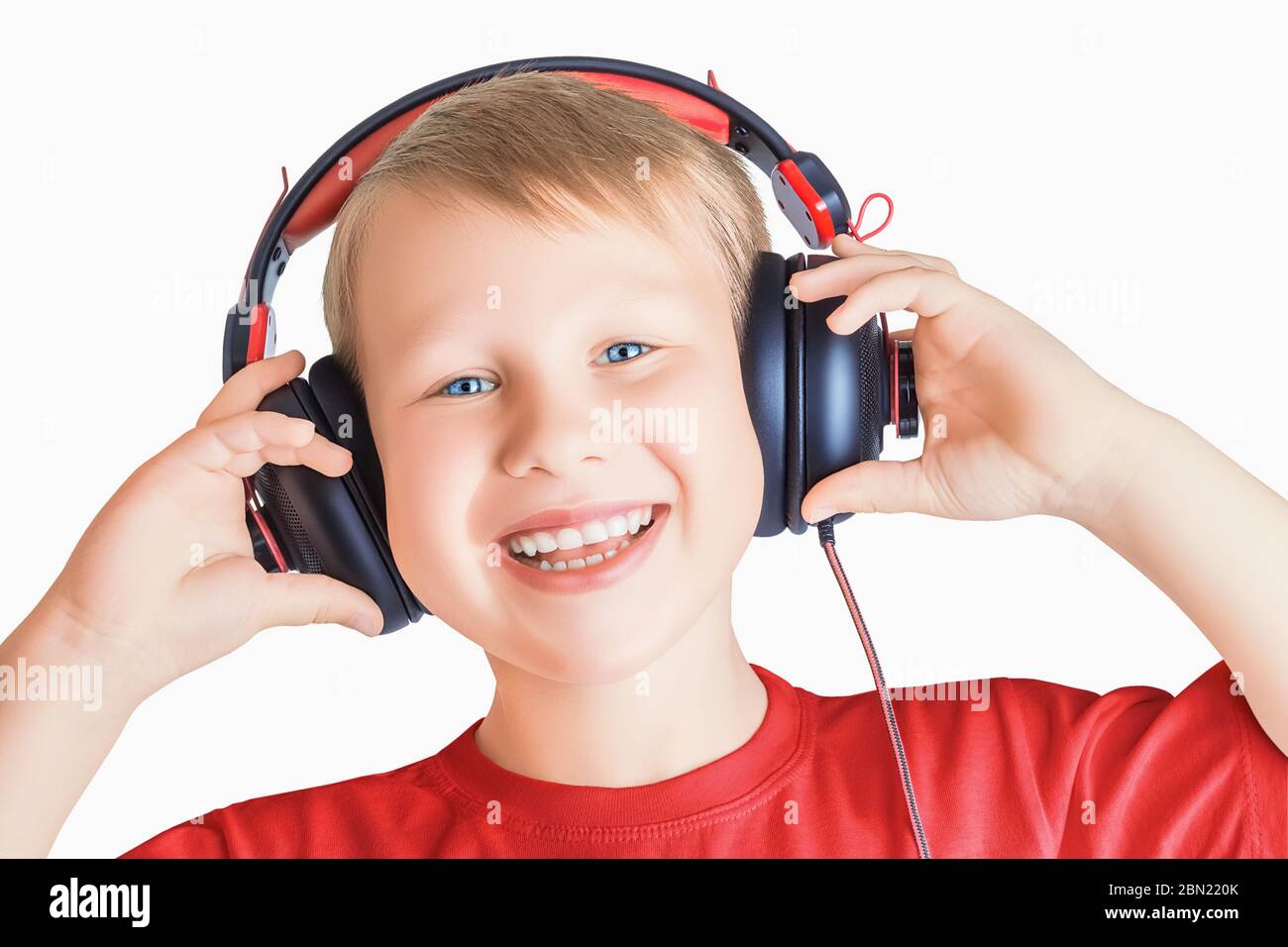 Joli et charmant, il écoute de la musique et tient les mains sur un casque isolé sur un fond blanc Banque D'Images