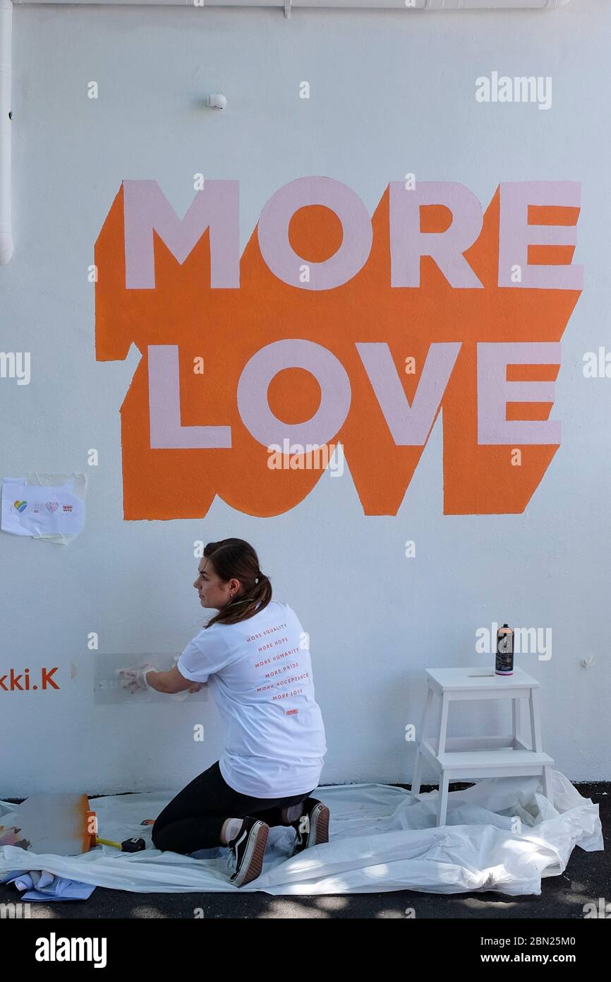 Femme mettant PLUS DE LOGO D'AMOUR sur le mur blanc à Carroll Street dans la banlieue de Melbourne de Richmond, Victoria, Australie Banque D'Images