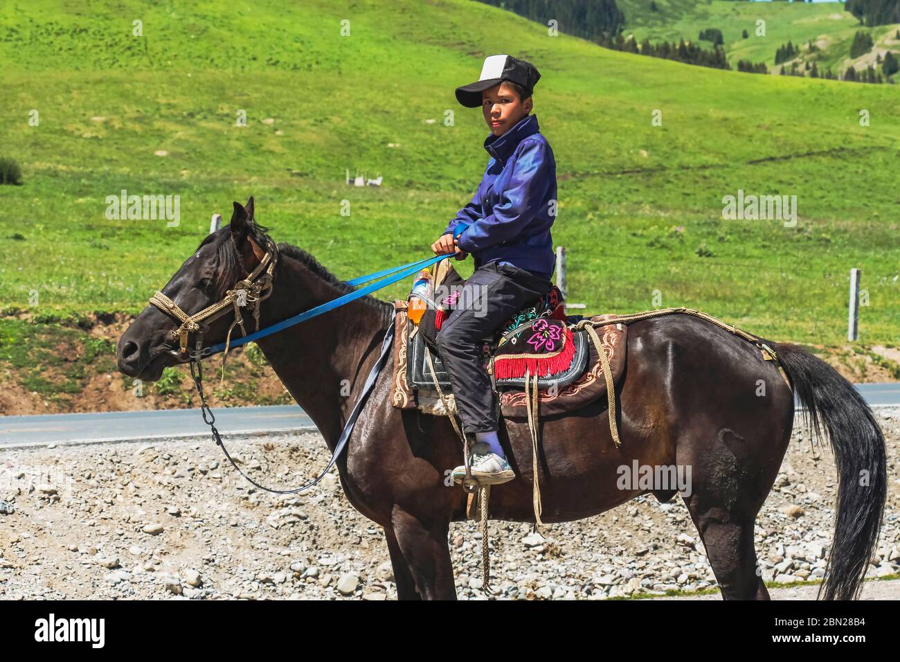 Province de Xinjiang, Chine - 11 juillet 2014 : un fermier uyghur sur son cheval se tourne pour une photo Banque D'Images