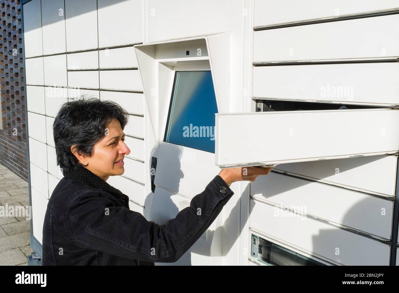 Femme asiatique britannique utilisant un casier postal automatisé, point de collecte de colis au Royaume-Uni Banque D'Images