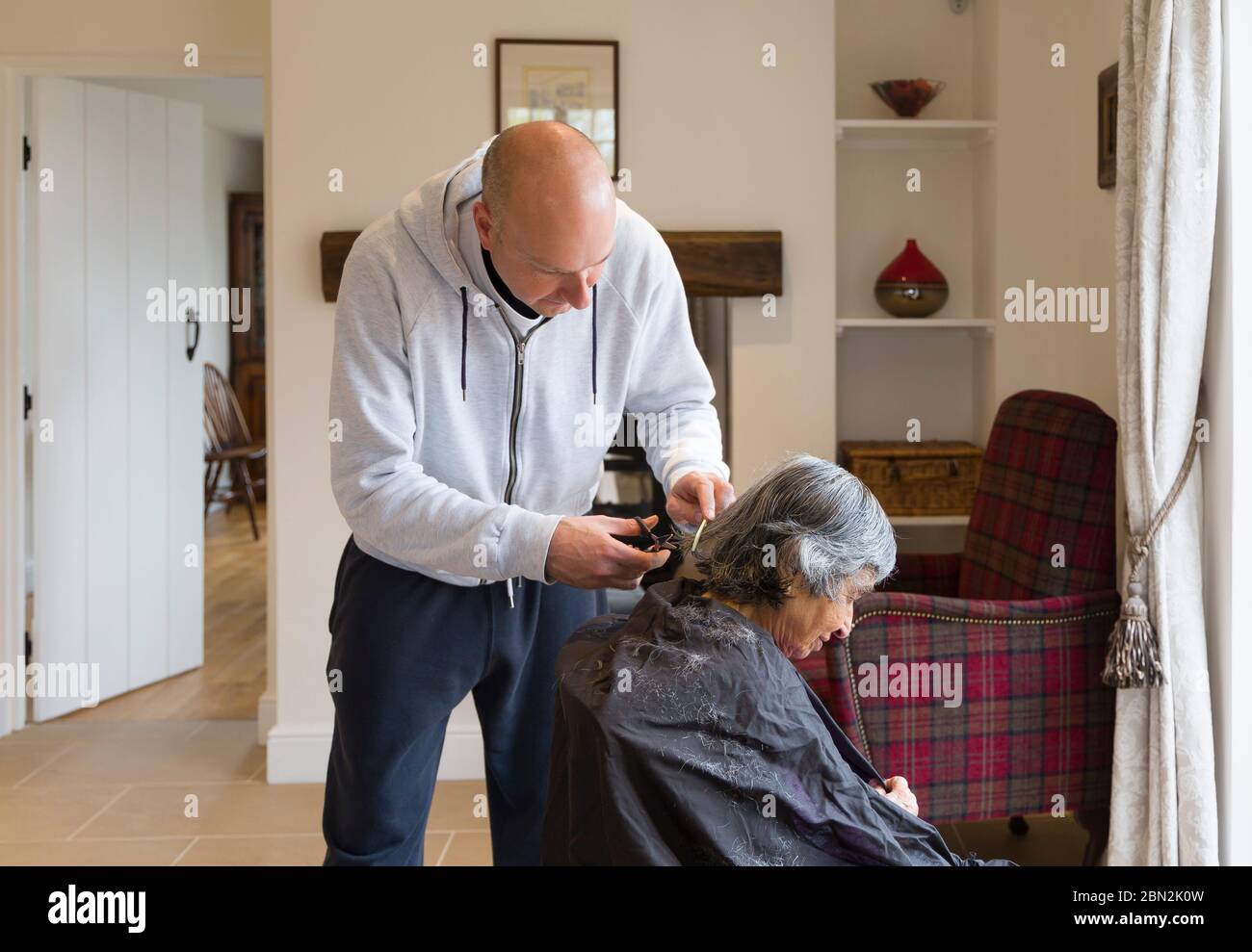 Femme âgée ayant une coupe de cheveux à la maison pendant le coronavirus, Royaume-Uni Banque D'Images