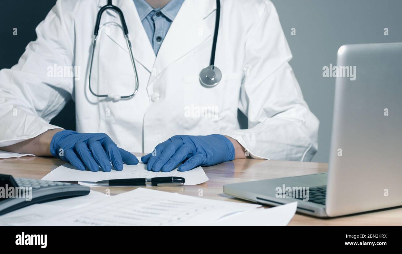 Médecin qui regarde les dossiers médicaux en collaboration avec le coputer Banque D'Images