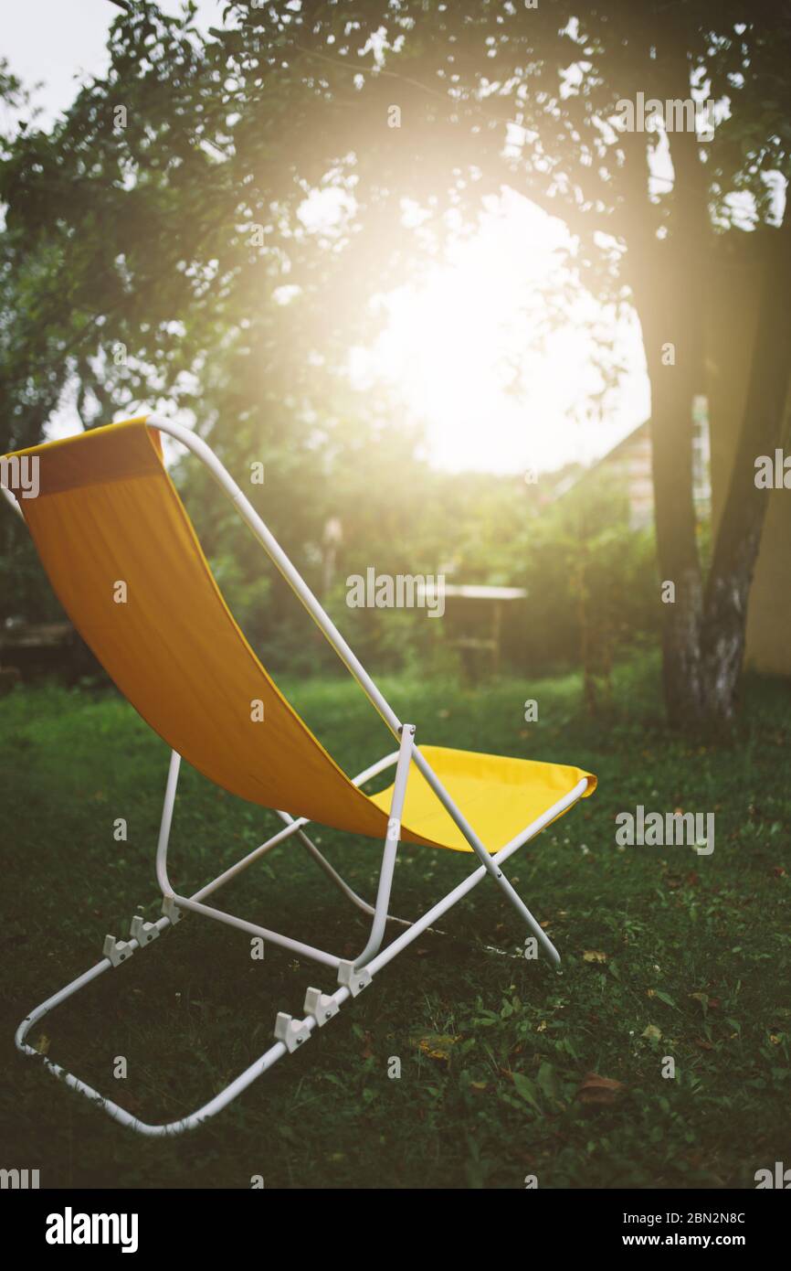 Chaise en tissu jaune vide dans le jardin d'été, concept reposant et relaxant, personne Banque D'Images