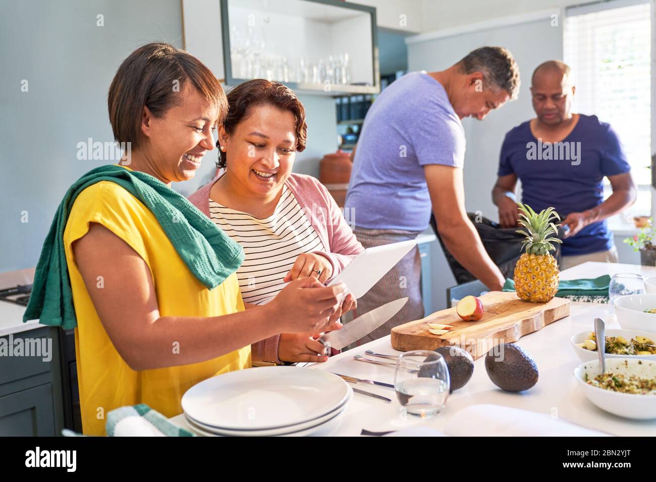 Couple heureux amis utilisant la tablette numérique et la cuisine dans la cuisine Banque D'Images
