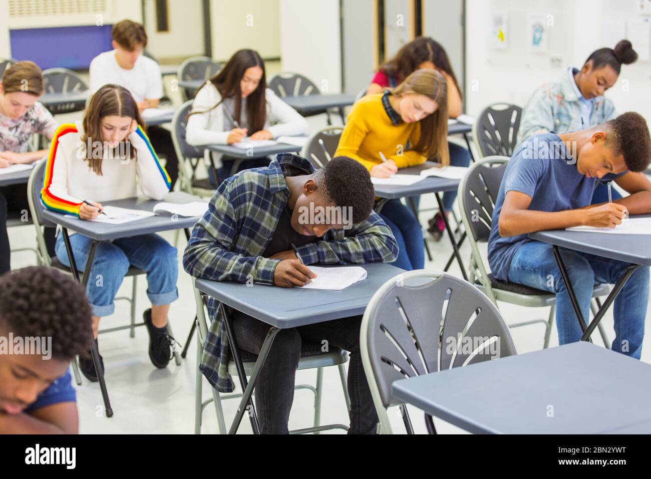 Élèves du secondaire ciblés qui se font passer un examen aux bureaux en classe Banque D'Images