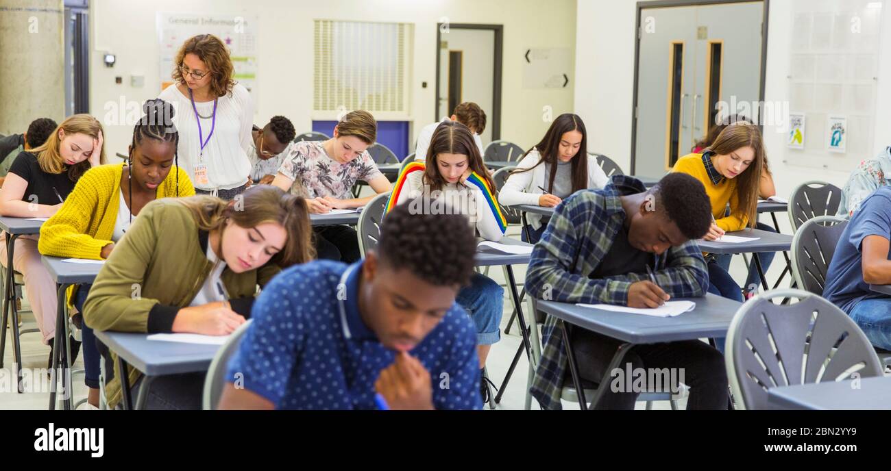 Enseignant du secondaire supervisant les élèves qui se font passer un examen aux bureaux Banque D'Images