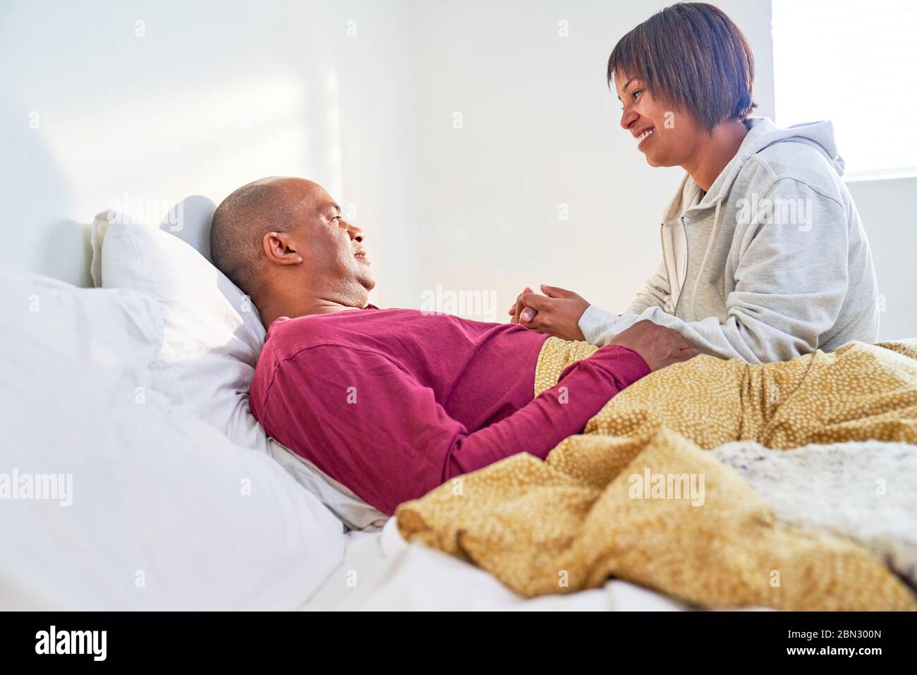 Femme de soin vérifiant sur mari malade se reposant dans le lit Banque D'Images
