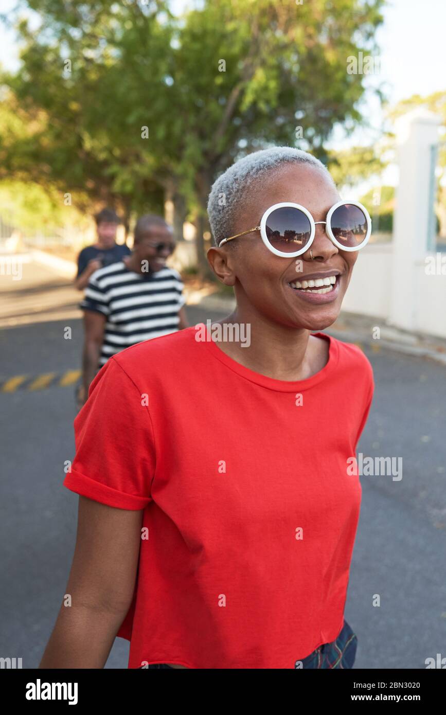 Bonne jeune femme dans des lunettes de soleil marchant dans la rue Banque D'Images