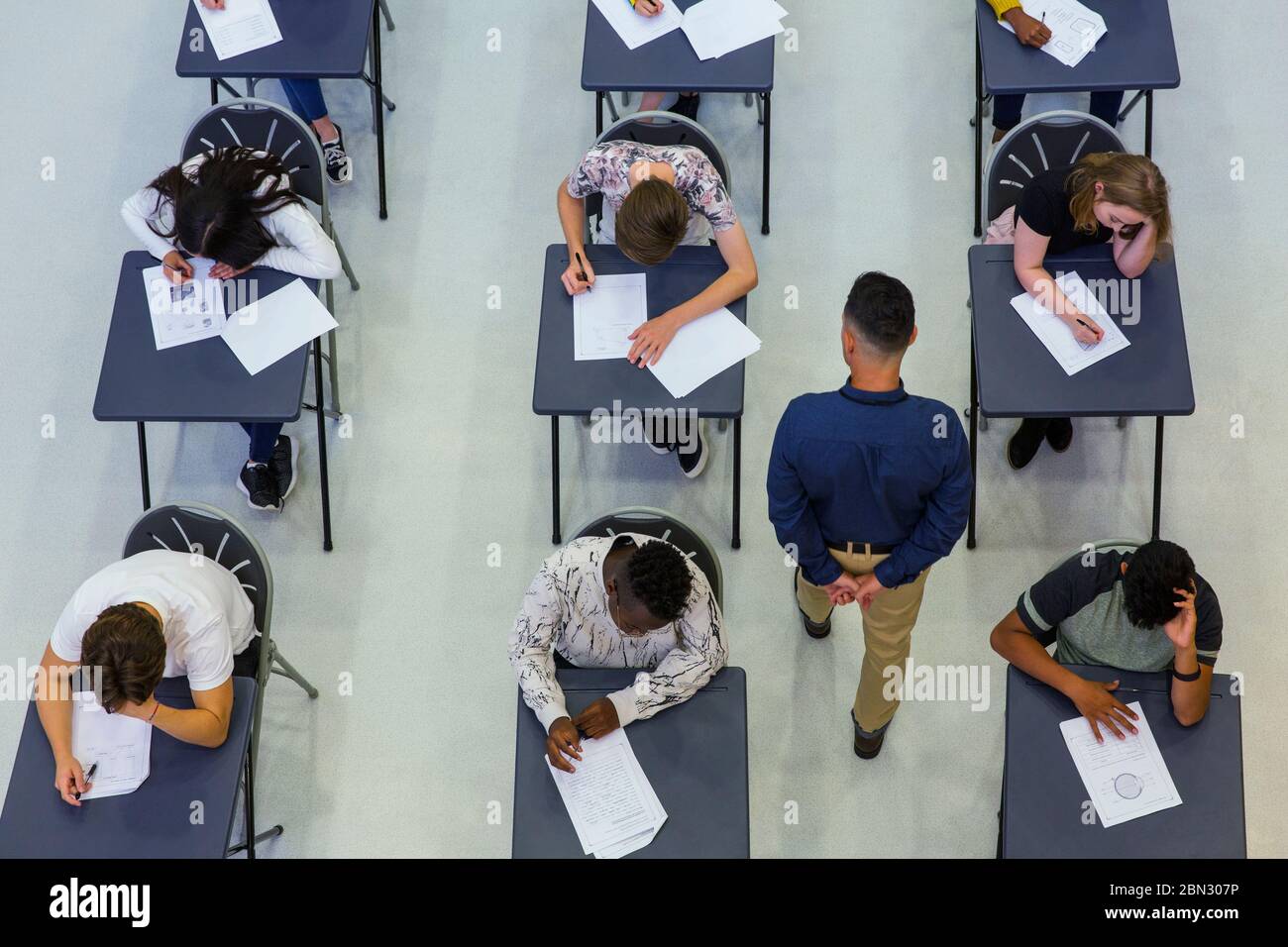 Enseignant du secondaire supervisant les élèves qui se font passer un examen aux bureaux Banque D'Images