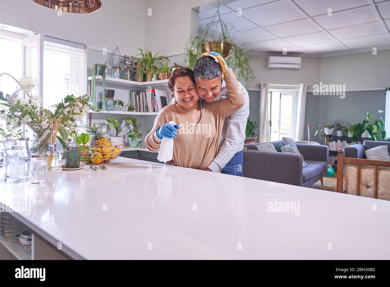 Affectueux couple mûr embrassant et nettoyant cuisine île Banque D'Images