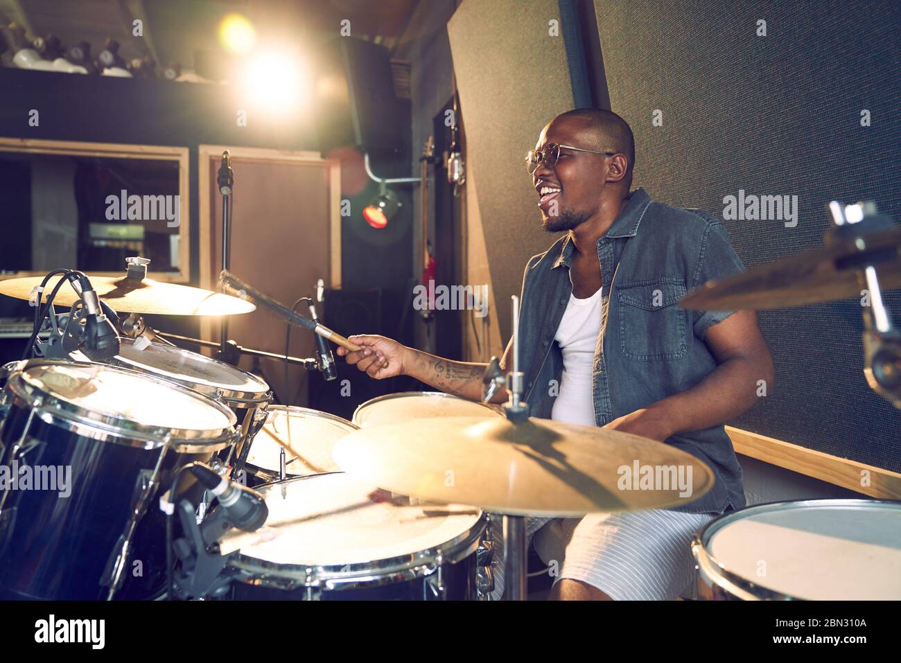 Musicien masculin jouant des tambours dans un studio d'enregistrement Banque D'Images