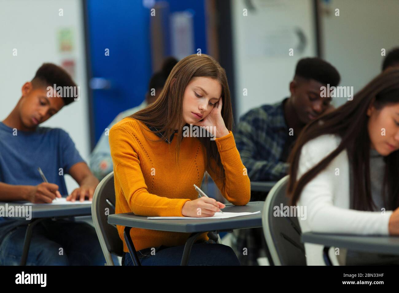 Jeune fille d'école secondaire ciblée prenant l'examen à bureau en classe Banque D'Images