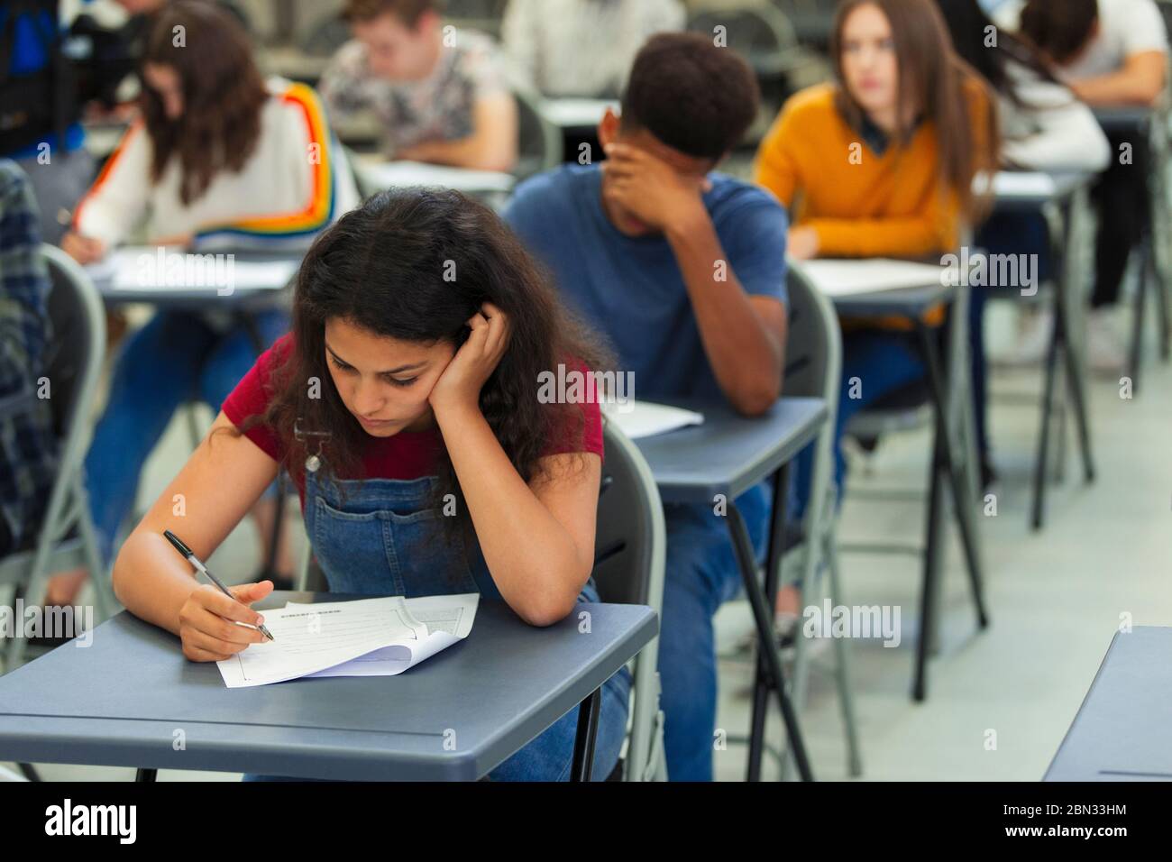 Jeune fille d'école secondaire ciblée prenant l'examen à bureau en classe Banque D'Images