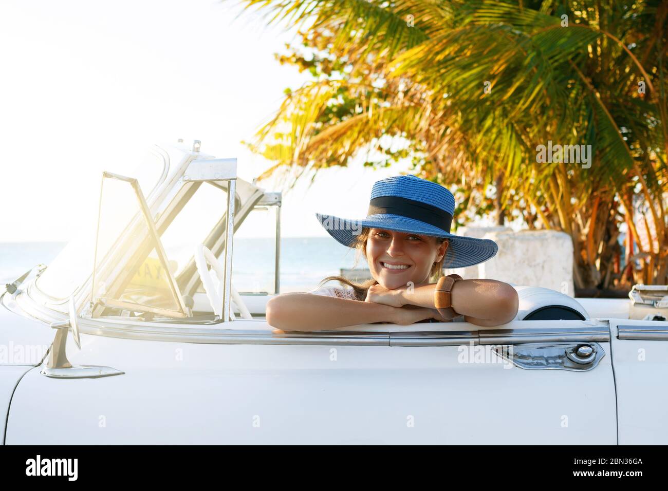 Belle femme en chapeau bleu et blanc rétro cabriolet sur la plage Photo  Stock - Alamy