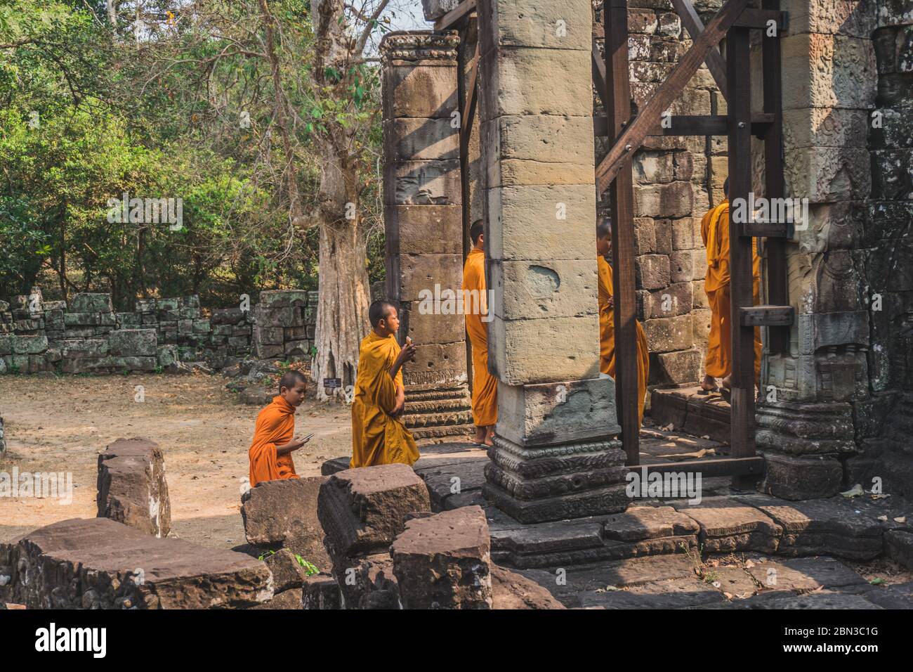 Jeunes Monks bouddhistes marchant dans le Temple dans des robes de Saffron et regardant sur Angkor Wat. Temple Banteay Kdei. Siem Reap, Cambodge - 25 FÉVRIER 2020 Banque D'Images