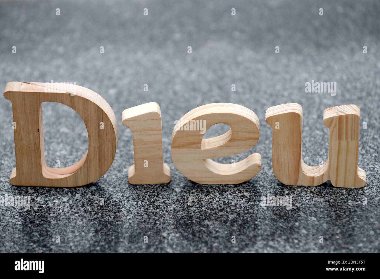 Lettres en bois formant le mot Dieu ( dieu ) sur fond de marbre noir. Symbole chrétien. Banque D'Images