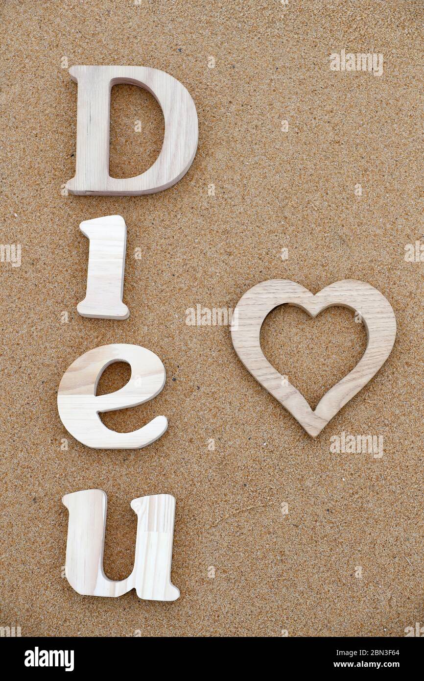 Dieu De L Amour En 4 Lettres Lettres en bois formant le mot Dieu ( dieu ) avec coeur sur fond de sable  de plage. Symbole chrétien Photo Stock - Alamy
