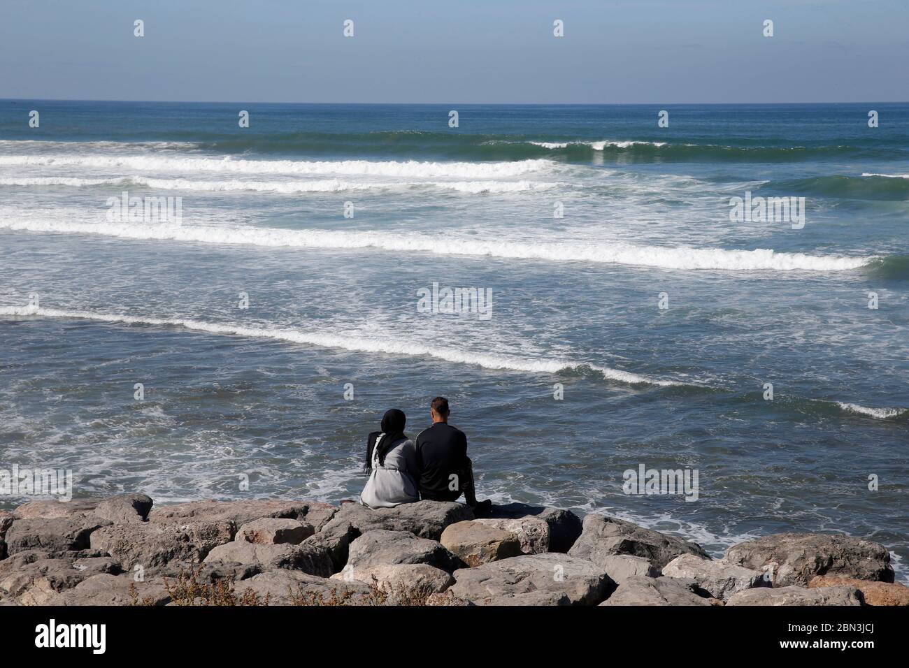 Jeune couple assis au bord de l'océan à Casablanca, Maroc. Banque D'Images
