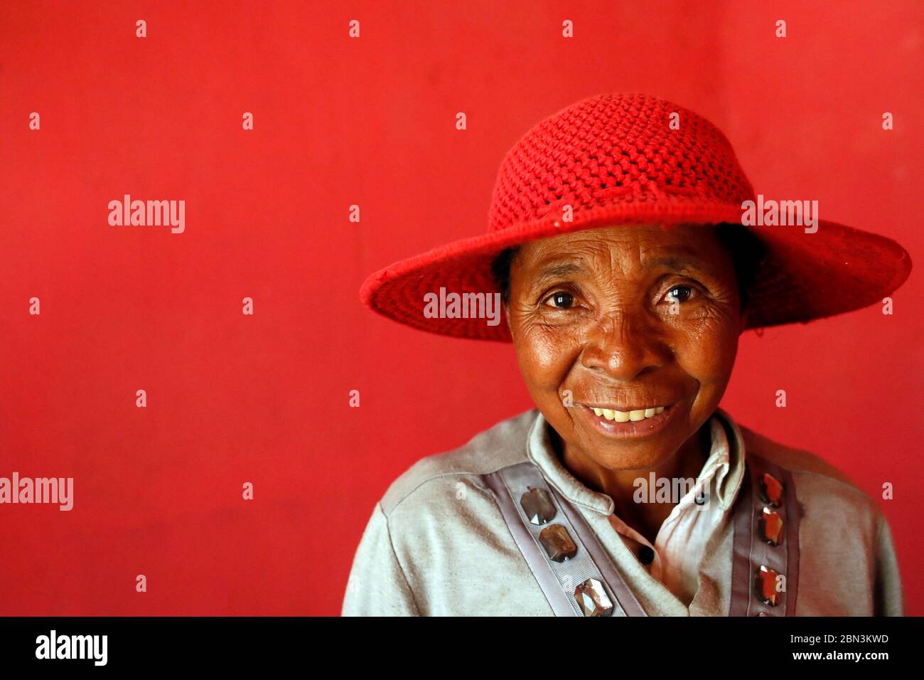 Femme malgache frayeuse avec un chapeau rouge. Portrait. Madagascar. Banque D'Images